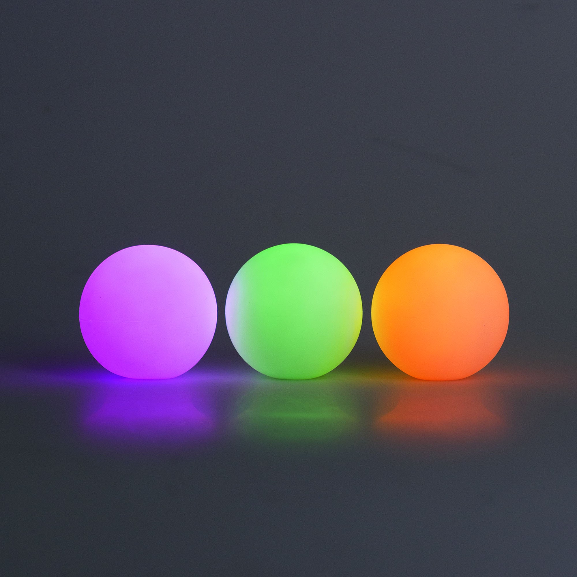 Three colorful balls (purple, green, orange) on a dark background