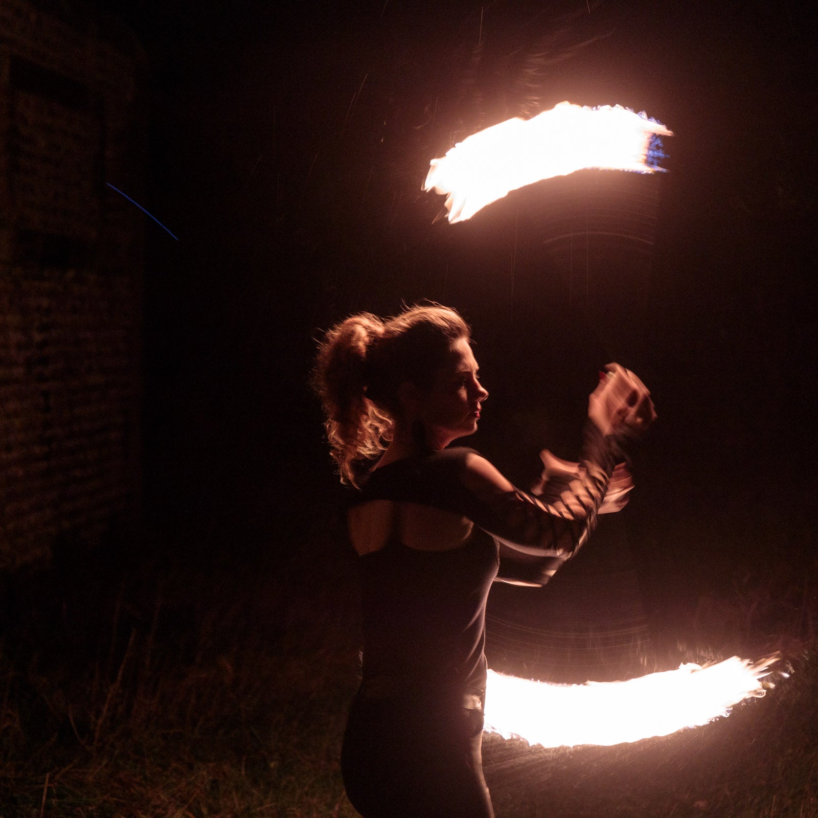a photo of a woman spinning the cathedral fire poi at night