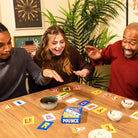 Three people playing a word game with cards on a wooden table.