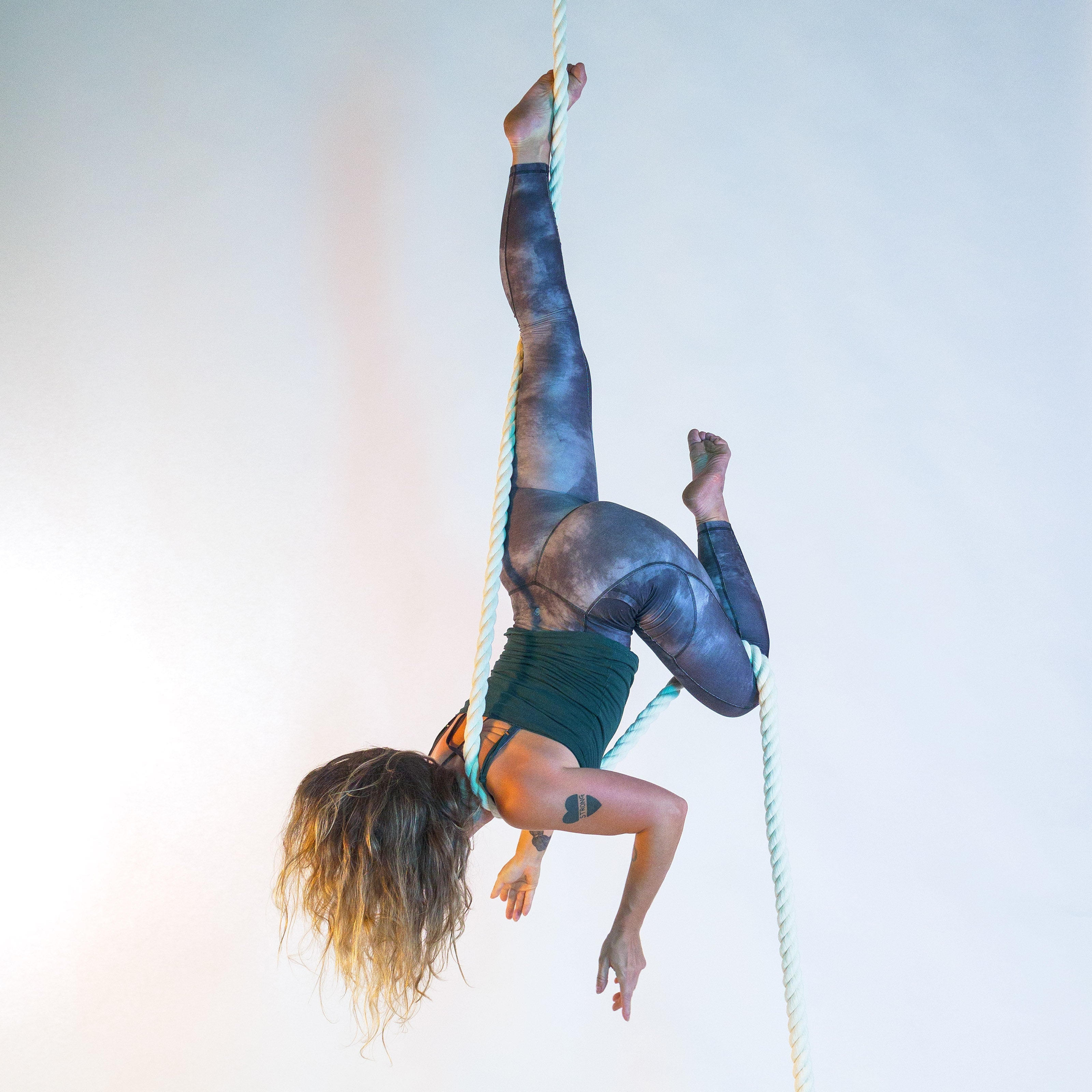 image of a performer hanging in a dart shape on a white 3ply rope