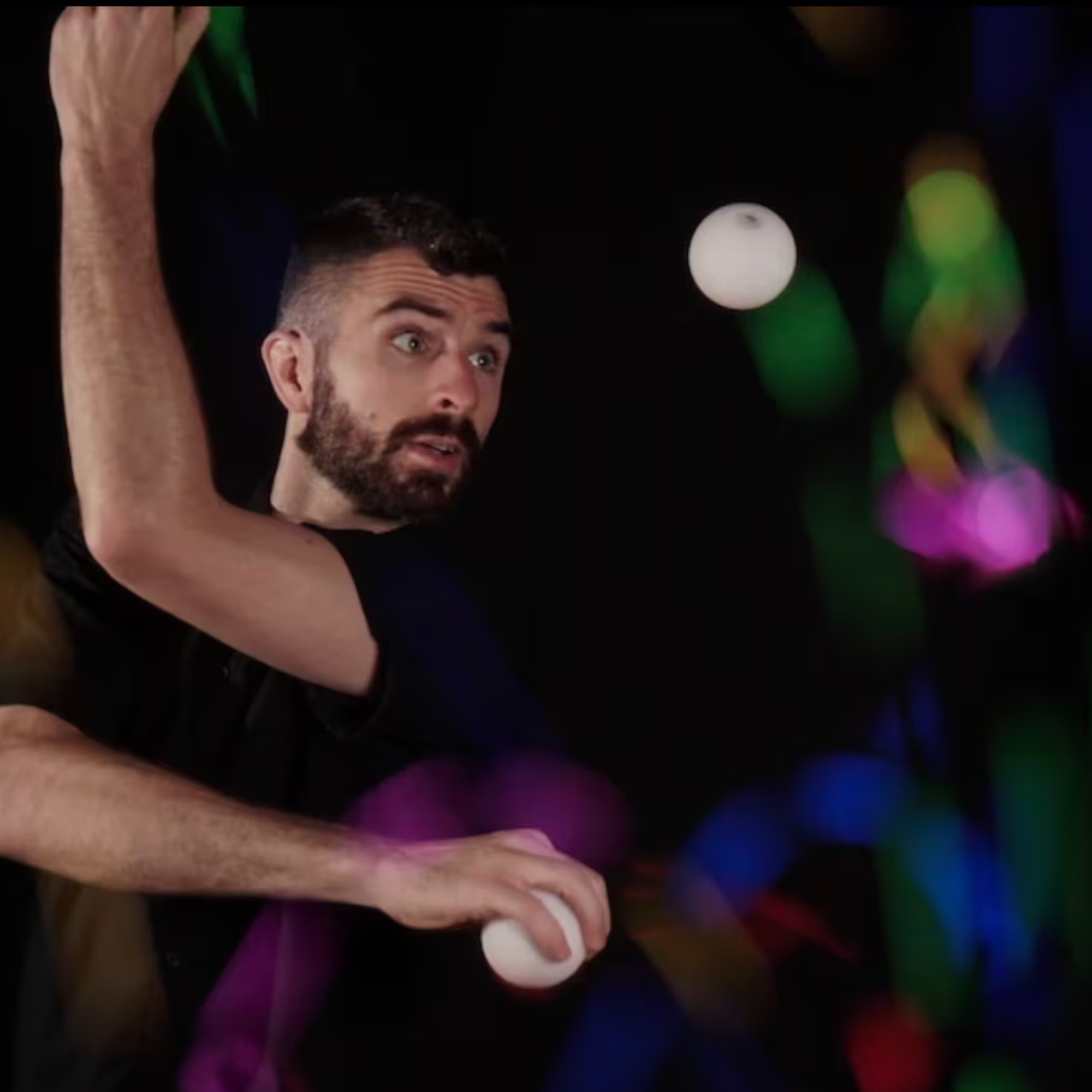 Man juggling with colorful lights in the background
