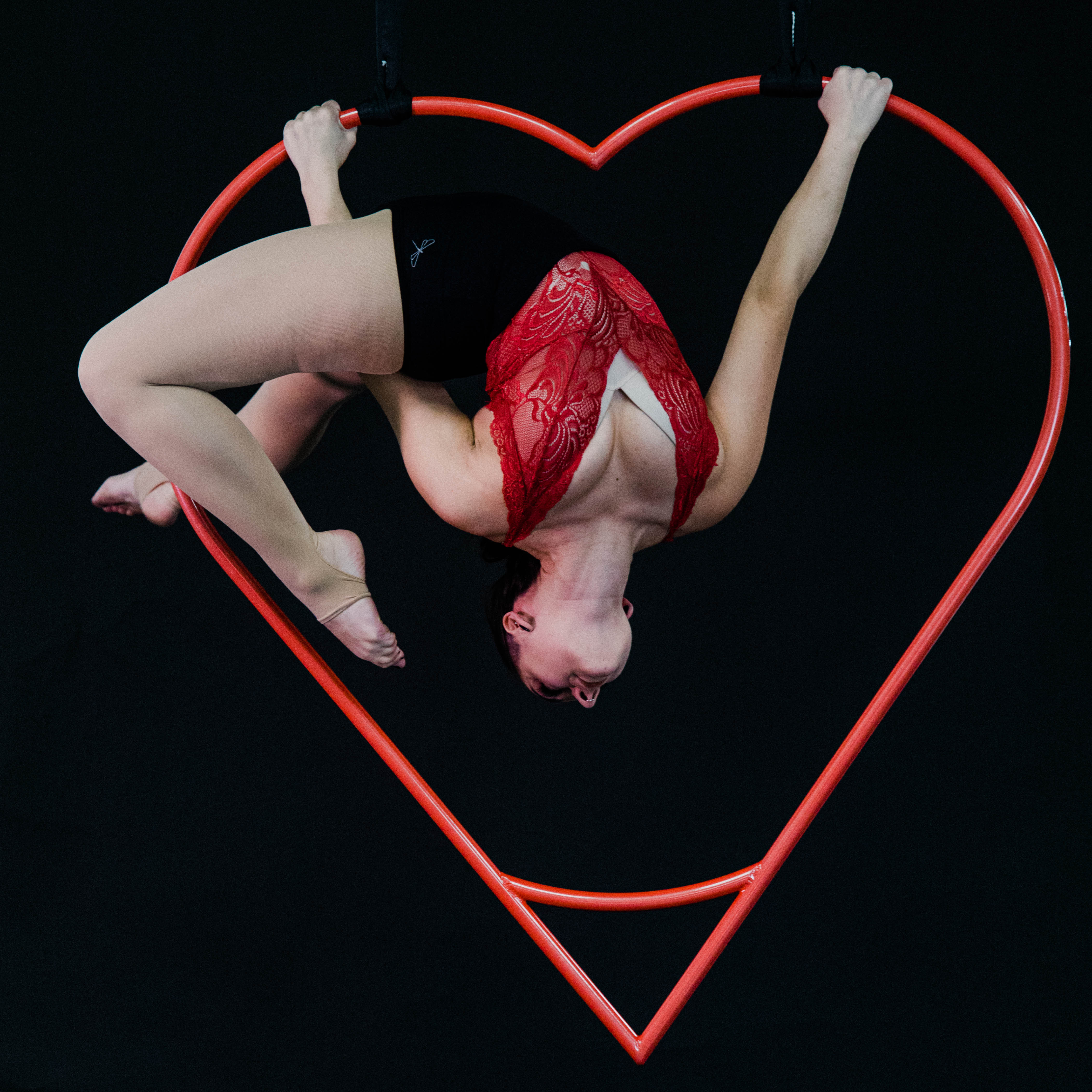 performer upside down inside the aerial heart hoop